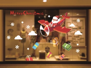 Close-up of Santa flying a red plane sticker on a glass window with festive snow details