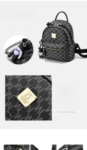 Détail d'un sac à dos en cuir noir avec monogramme, finitions dorées et charm d'ours