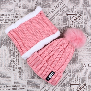 Detail of pink knitted hat with thick white faux fur lining and plush pompom top