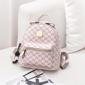 Mini sac à dos rose avec motif M, détail nœud et pendentif ours sur canapé blanc