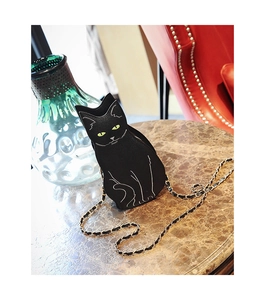 Close-up of black cat-shaped crossbody bag with gold chain strap on marble table