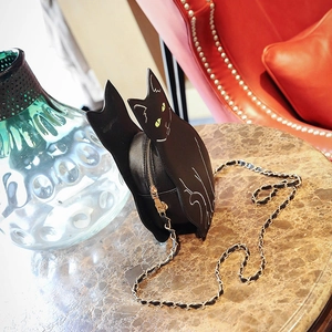 Close-up of black cat-shaped crossbody bag with white lines and golden chain strap