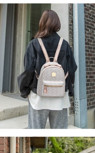 Detail of elegant monogram travel backpack with golden zippers and smooth leather handle
