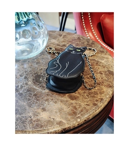 Detail view of black cat-shaped crossbody bag with green eye embroidery and gold chain