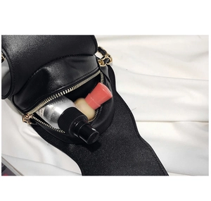 Detail of black leather bag with gold chain strap showing open interior and items