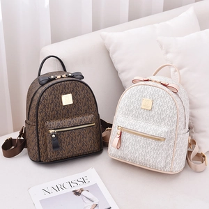 Faux leather mini backpacks with floral patterns and bow details on a white sofa