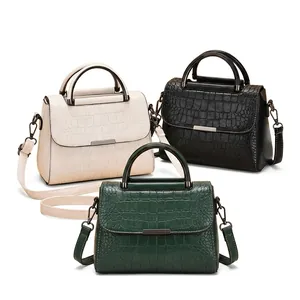 Detail view of crocodile pattern leather handbags in cream, black, and green colors