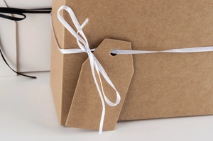 Detail of a brown kraft paper hexagonal favor box with a white silk ribbon and tag