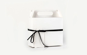 Detail of white kraft paper gift box featuring a black ribbon and blank hanging tag