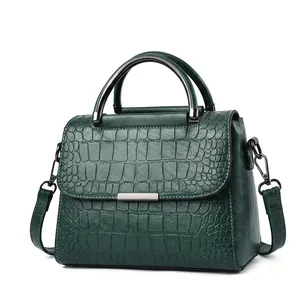 Detailed close-up of dark green crocodile embossed handbag with metal chain strap and handle