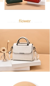 Detail view of white crocodile pattern bag with black handle and gold metal trim