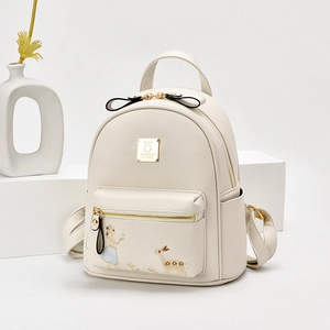 Mini sac à dos beige élégant en cuir brodé présenté sur un support de studio blanc