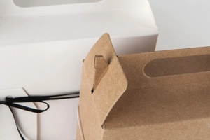 Macro shot of white and kraft paper gift boxes showing handle and buckle closure details