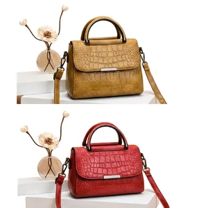 Detail of crocodile embossed crossbody bag in ginger yellow and red leather texture