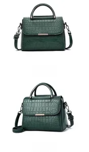Detail of dark green crocodile texture handbag with silver metal ring handle and strap