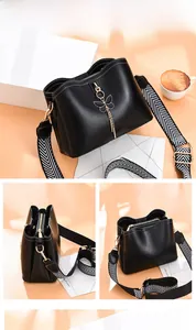 Vue détaillée du sac seau noir avec breloque papillon et bandoulière tissée à motifs