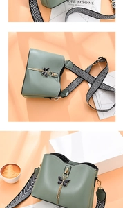 Vue détaillée du sac bandoulière vert sauge avec pendentif papillon et bandoulière rayée