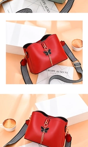 Détail du sac seau rouge avec pompon papillon et bandoulière tissée noir et blanc
