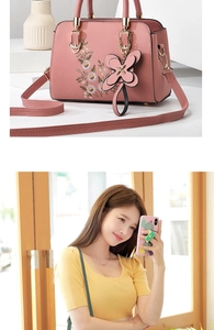 Detail of pink handbag with floral embroidery and butterfly charm shown on model