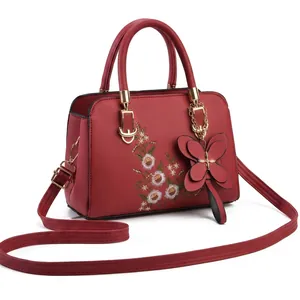 Close-up of floral embroidery and butterfly pendant on luxury faux leather handbags