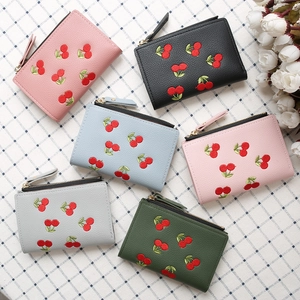 Flat lay of short wallets in six colors with cherry embroidery and zipper closure