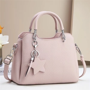 Pink lychee texture leather handbag with silver hardware and star charm on beige background