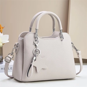 Chic beige lychee leather handbag with star charm and silver hardware shown with decor