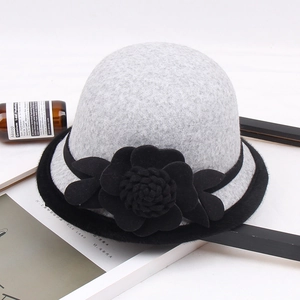 Detalle de sombrero de lana gris para mujer con flor negra y borde de piel sintética
