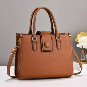 Détail du sac à bandoulière en cuir marron grainé avec boucle dorée et fermeture à rabat