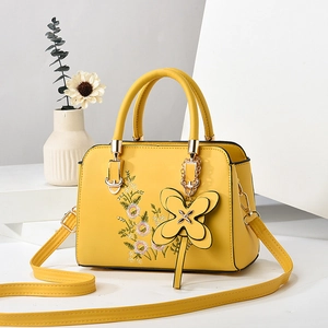 Elegant yellow faux leather tote with floral embroidery and gold butterfly charm