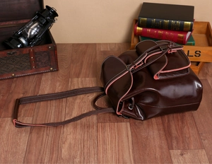 Detail of dark brown vintage oil-wax leather backpack in a retro setting with oil lamp