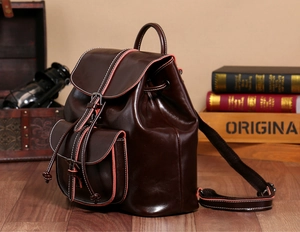 Detailed side view of dark brown wax leather backpack with vintage pocket and white stitching