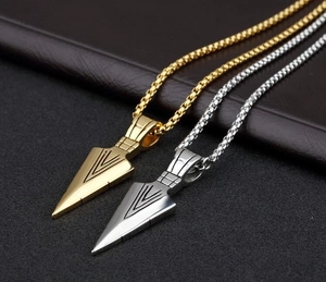 Close-up of gold and silver arrow pendant necklaces on a dark leather texture