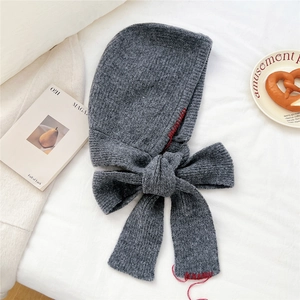 Détail de la cagoule en tricot gris foncé avec coutures rouges et nœud élégant