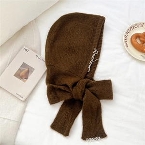 Détail de cagoule en tricot marron foncé avec coutures blanches faites à la main