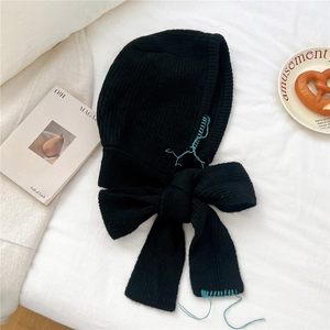 Détail de l'écharpe à capuche noire avec couture bleue contrastée et grand nœud décoratif