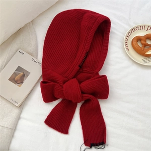 Détail de la cagoule tricotée rouge avec coutures noires et fermeture par nœud papillon