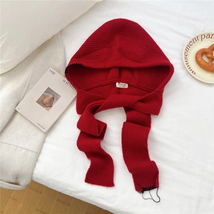 Détail de la capuche écharpe rouge tricotée avec étiquette et texture en laine