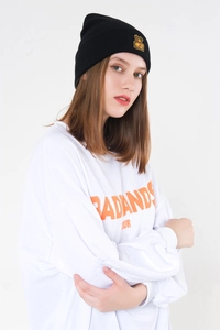 Close-up of a black knit beanie with golden monkey embroidery on a white background