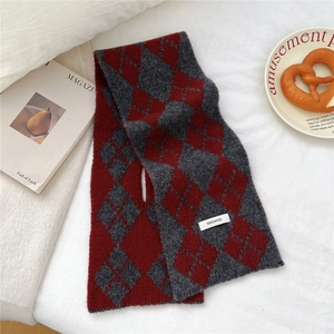 Detailed view of red and grey argyle wool knit scarf with cross-over hole design