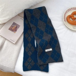 Detail shot of the 100% wool knit scarf featuring a classic navy blue diamond pattern