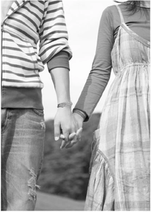Romantic black and white photo of a couple holding hands wearing layered leather bracelets