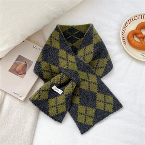 Detail of cross-insert argyle knit wool scarf in grey and olive green on a white bed