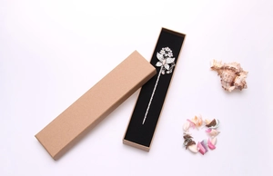 Detailed view of a silver butterfly hair pin with rhinestones in a kraft paper gift box
