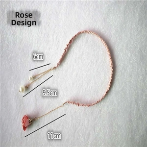 Detailed view of pink braided headband with red rose pendant and white pearls