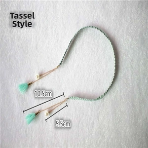 Detail view of mint green woven headband with white pearls and gold tassel charms