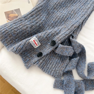 Macro detail of melange blue-grey knit texture with black buttons and brand label