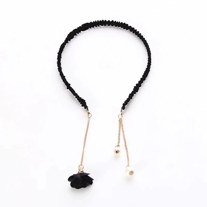 Detail view of black fabric headband featuring gold tassel chains and pearl pendants