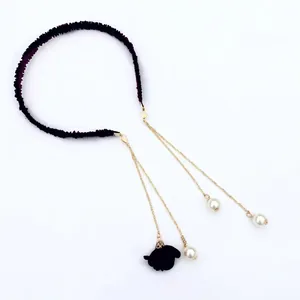 Detail of velvet headband with golden chains, white pearls and black flower charms