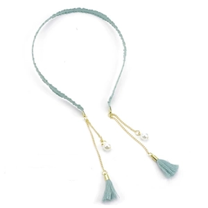 Detail of light blue fabric headband with golden chains, faux pearls and tassel pendants